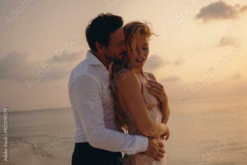 Young couple embracing during sunset on the beach, showcasing love and luxury