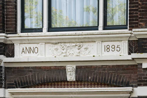 Historic building facade detail with “ANNO 1895” inscription and decorative stucco relief on a brick townhouse. Vlaardingen, Netherlands.