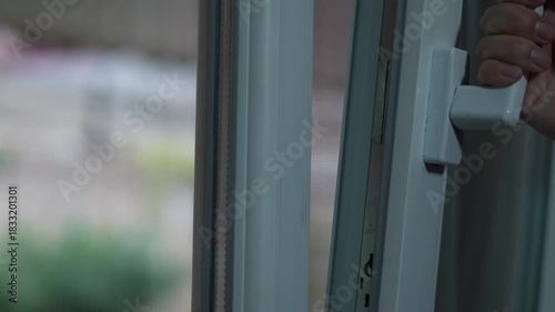 Man opens a white plastic window at home