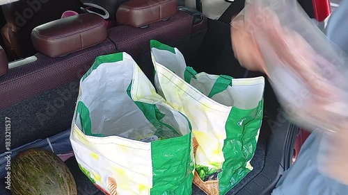Timelapse of a woman loading supermarket groceries into reusable shopping bags in the trunk of a car, organizing items quickly and efficiently during a routine shopping task