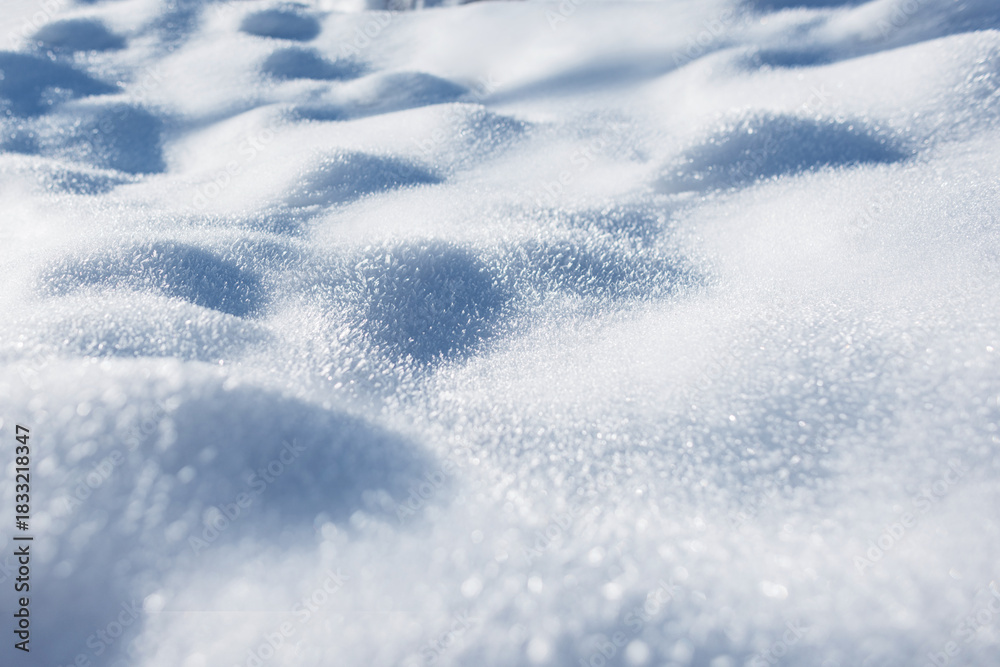 Obraz premium soft, close-up view of fresh, untouched snow shimmering in bright sunlight. The surface shows gentle curves and subtle shadows, highlighting the sparkling texture of the snow crystals. Winter snow.