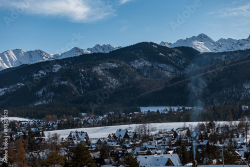 Fototapeta Naklejka Na Ścianę i Meble -  Picturesque Zakopane, a Polish mountain resort. Snowy homes and dark forests contrast with the sharp, white peaks of the Tatra Mountains (Tatry)