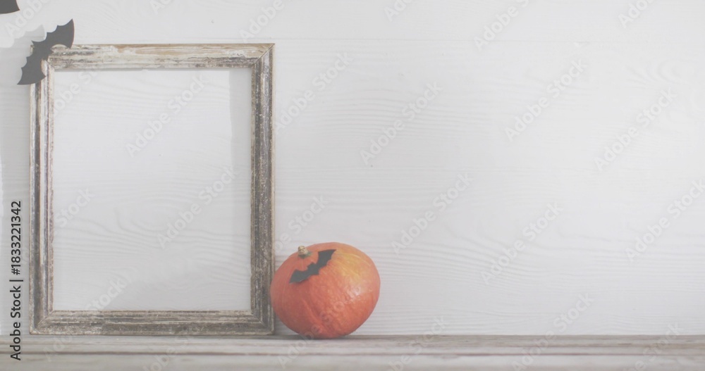 Naklejka premium Displaying small orange pumpkin sitting on worn tabletop with frame and bat cutouts, copy space