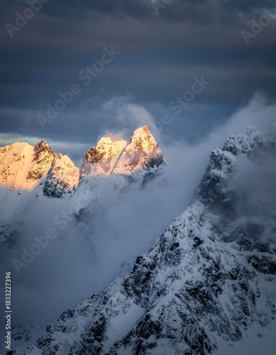 Majestic Snow-Capped Peaks Rising Above Clouds at Dusk