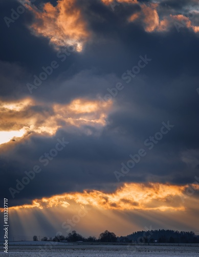 Dramatic Sunset with Dark Clouds and Rays of Light Over Landscape