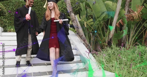 Two graduates starting descent on white steps, holding diplomas, shaking hands, marking graduation