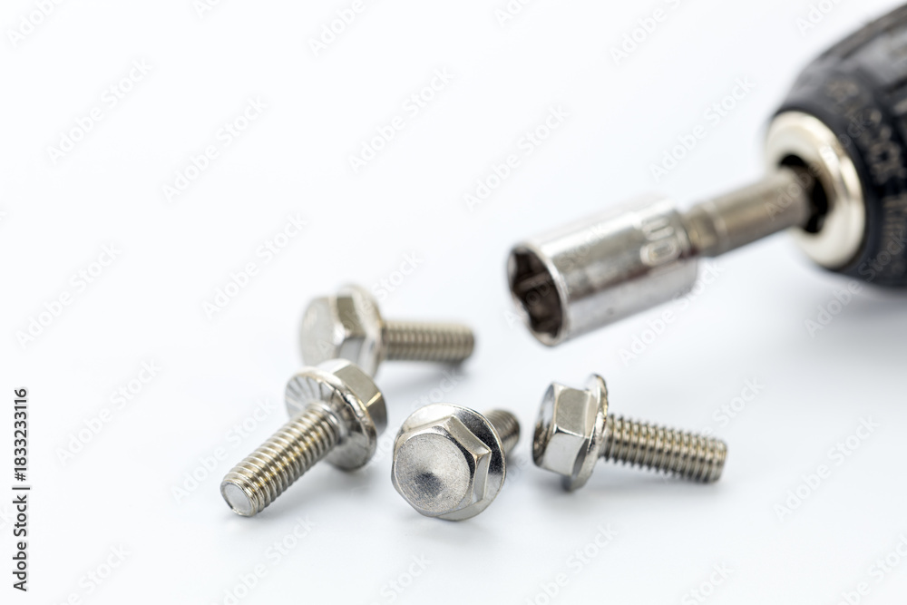 Fototapeta premium Four steel hex bolts placed on a white surface with a close-up of a socket wrench and metallic socket attachment for hardware
