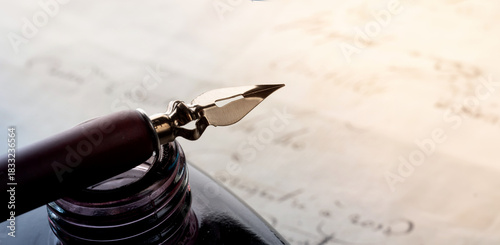 Fountain pen on an antique inkwell. Vintage nib pen and handwritten. Old history background. Retro style.