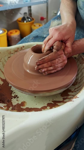 Close-up of a craftsman's hands skillfully shaping a piece of pottery from wet clay on a spinning wheel