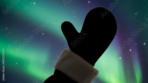 Silhouette of a black mitten with white trim against a vibrant green and purple aurora borealis sky filled with stars