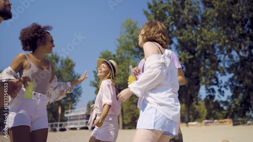 A joyful group of friends celebrating together at a beach party during sunset.