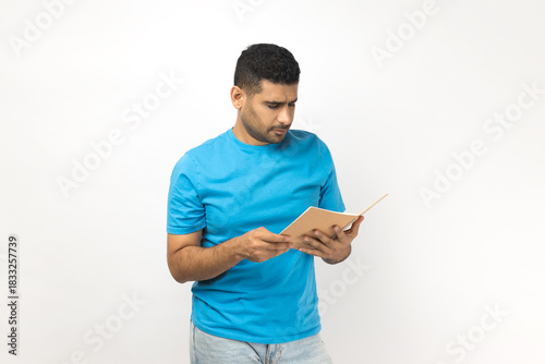Srious concentrated man holding book, reading interesting novel, being interested in plot.