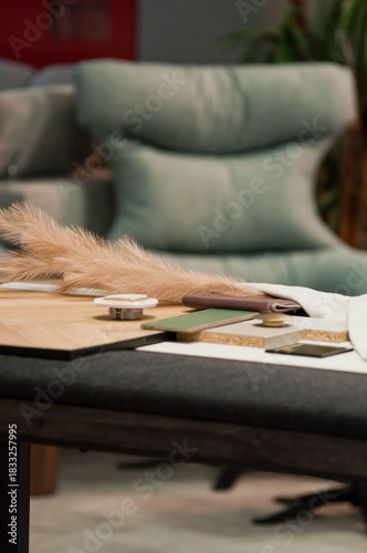 A display of ceramic tile samples in various neutral tones arranged in a showroom. The collection includes stone-texture and matte-finish tiles, creating a professional interior design workspace setti