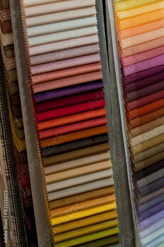 A display of ceramic tile samples in various neutral tones arranged in a showroom. The collection includes stone-texture and matte-finish tiles, creating a professional interior design workspace setti
