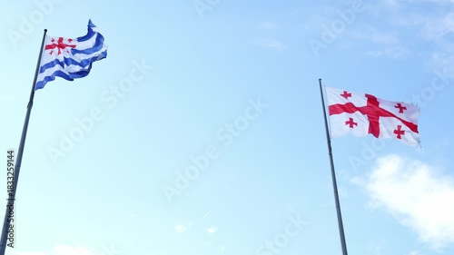 The flag of Georgia and Adjara is fluttering against the sky, taken by a drone in the city of Batumi in Georgia on the Black Sea. Aerial photography. The flag of Georgia and Adjara.