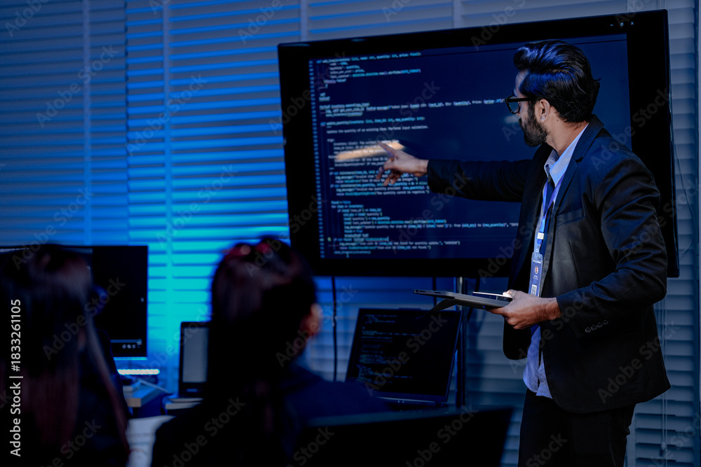 Fototapeta premium A focused male AI solutions architect in a futuristic control hub debates generative AI applications collaborating on a complex machine learning model with his team under atmospheric blue lighting.