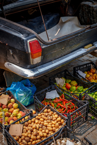 Street vendor selling vegetables from open car trunk