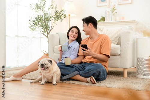 Young Asian Couple Relaxes at Home With Their Pug While Enjoying a Cozy Moment Together
