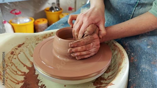 Close-up of a craftsman's hands skillfully shaping a piece of pottery from wet clay on a spinning wheel