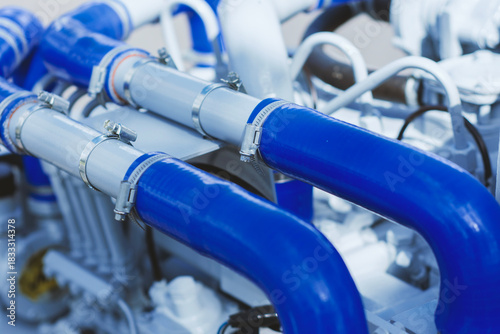 Close-up of bright blue silicone coolant or air intake hoses connected to grey piping using durable metal clamps on a modern engine.
