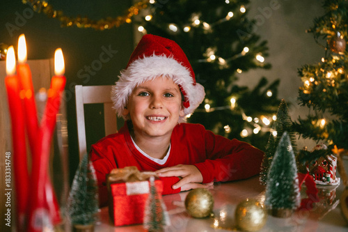 Merry Christmas and happy holidays. A cheerful funny boy 7 y.o. with a gift. A child is having fun near a tree.