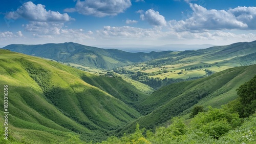 Wallpaper Mural Lush green rolling hills and valleys under a bright blue sky with scattered white clouds, showcasing a vast natural landscape Torontodigital.ca