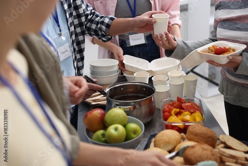 Photos Volunteers giving food to homeless people in shelter, closeup