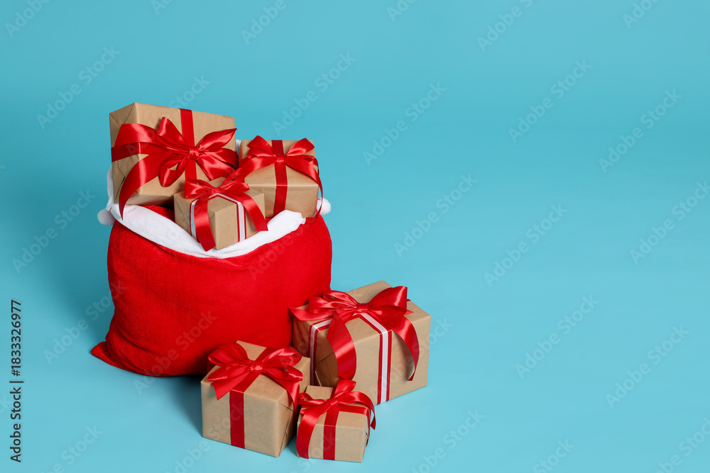 Obraz premium Santa Claus bag with Christmas gifts on light blue background, space for text