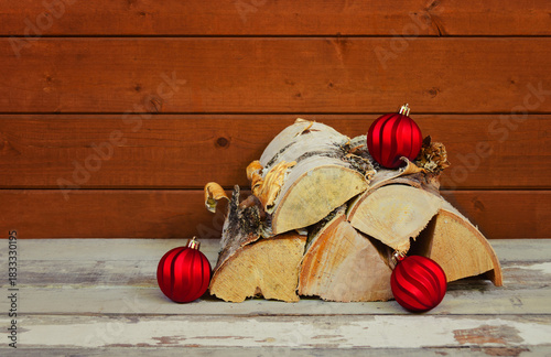 Christmas balls and pile of firewood on aged wooden surface. View with copy space.