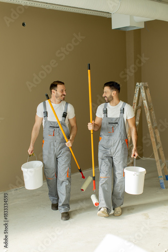 Two workers carry paint sup...