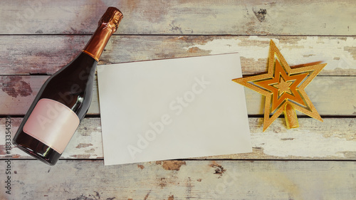Bottle of champagne and christmas tree topper with empty card for your notes. Aged wooden background.