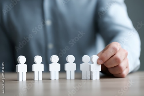 Hand selecting figurine from lineup of white figures on table