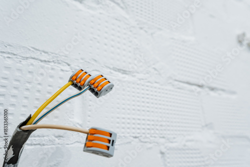 wallmounted wire terminal details, detailed view of connectors attached to cables inside wall, productfocused image featuring wire terminals connected to colored cables within wall cavity