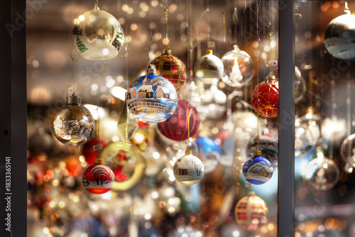 Painted glass baubles for sale behind a shop window at a Christmas market, seasonal business with holiday decoration, selected focus