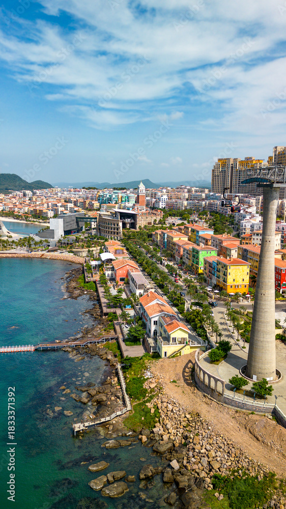 Fototapeta premium Aerial view of Sunset Town in Phu Quoc with colorful buildings, the coastal cable car, and the Kiss Bridge. Scenic tropical waterfront and vibrant seaside architecture in Vietnam.