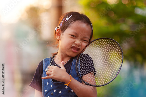 A cute Asian girl holds a badminton racket while exercising in the evening.