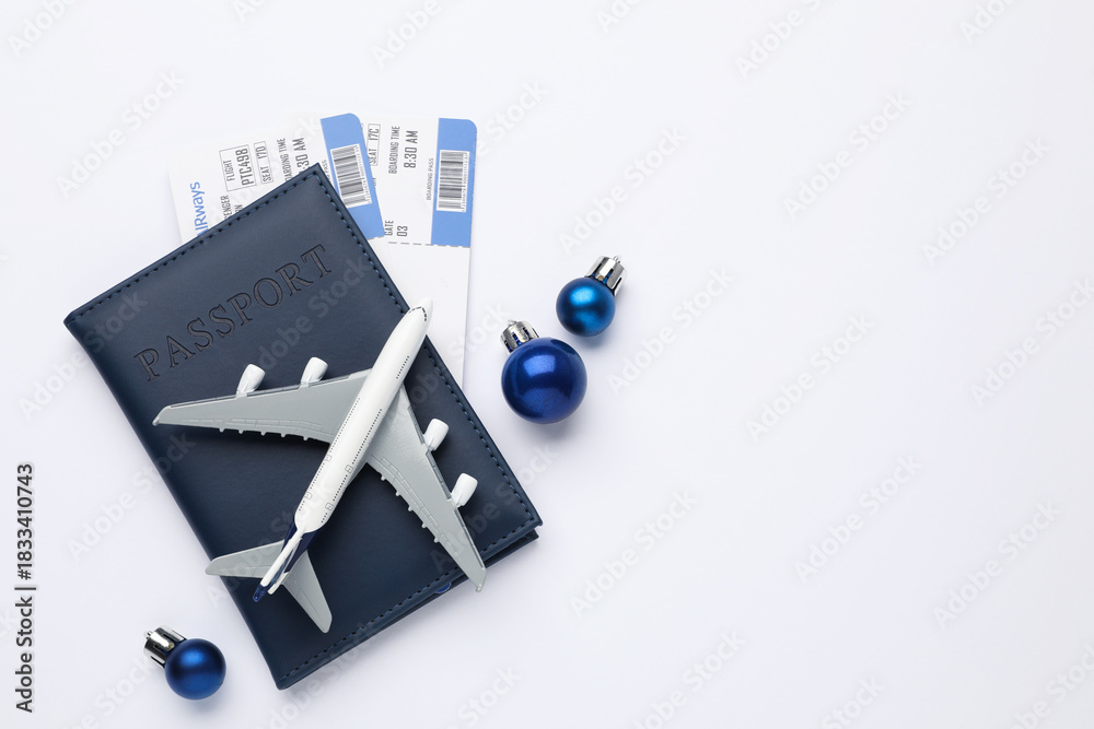 Naklejka premium Christmas vacation. Passport with tickets, plane model and ornaments on white background, flat lay. Space for text