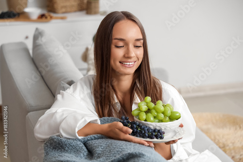 Young woman with grapes sit...
