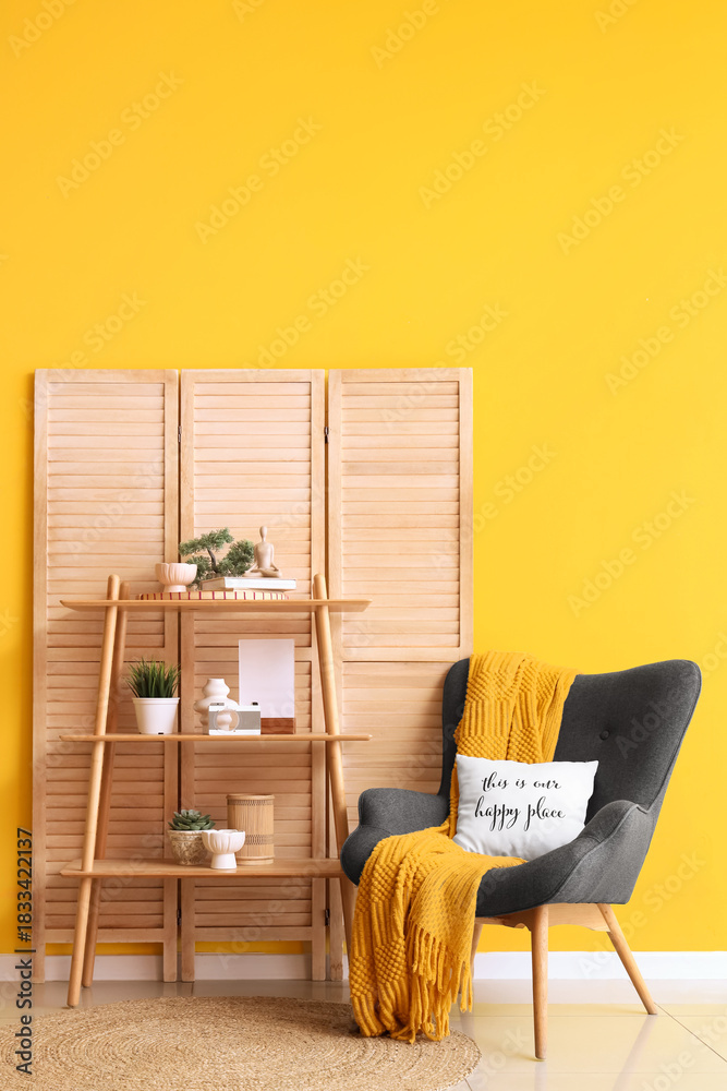 Fototapeta premium Interior of living room with wooden folding screen, shelf unit and armchair