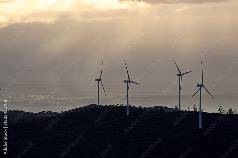 Obraz premium Wind Turbines Over Hills at Sunset 