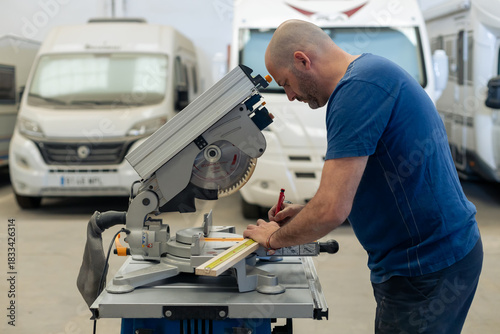 A young craftsman restores a caravan in a hangar.