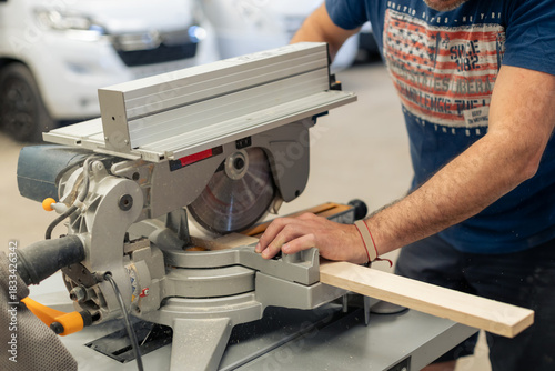 A young craftsman restores a caravan in a hangar.