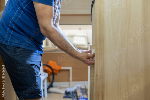 A young craftsman restores a caravan in a hangar.