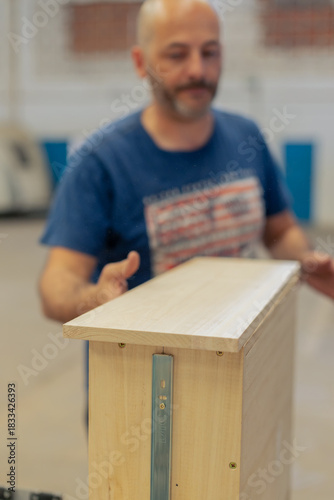 A young craftsman restores a caravan in a hangar.