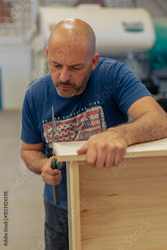 A young craftsman restores a caravan in a hangar.
