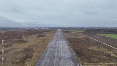 A deserted concrete runway of a former Soviet military airbase in Kedainiai, Lithuania. Overcast sky, rural fields, and decaying aviation infrastructure