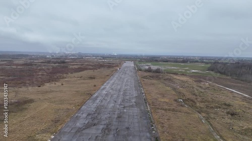 A deserted concrete runway of a former Soviet military airbase in Kedainiai, Lithuania. Overcast sky, rural fields, and decaying aviation infrastructure