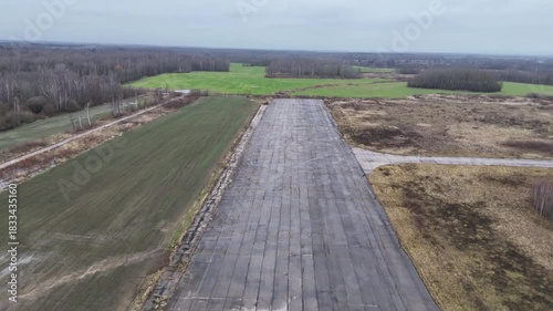 A deserted concrete runway of a former Soviet military airbase in Kedainiai, Lithuania. Overcast sky, rural fields, and decaying aviation infrastructure