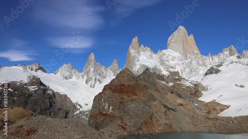 Fitzroy mountain in Patagonia with sharp granite peaks rugged terrain drifting clouds clear sky remote wilderness glacial valley rocky landscape natural environment and panoramic daylight view scenery