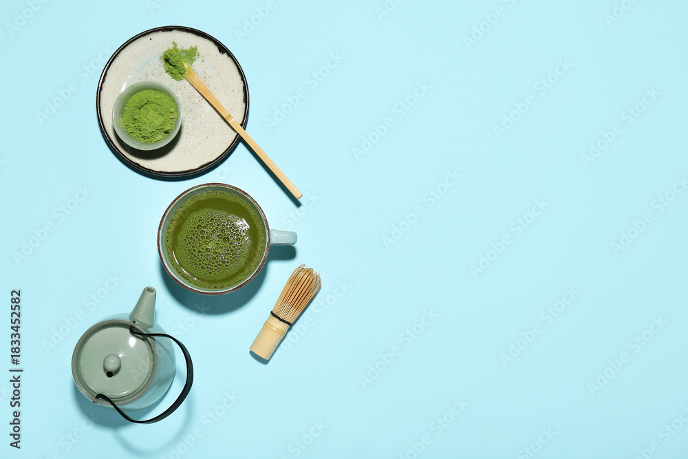 Naklejka premium Cup of fresh matcha tea with powder, chasen, chashaku and teapot on blue background